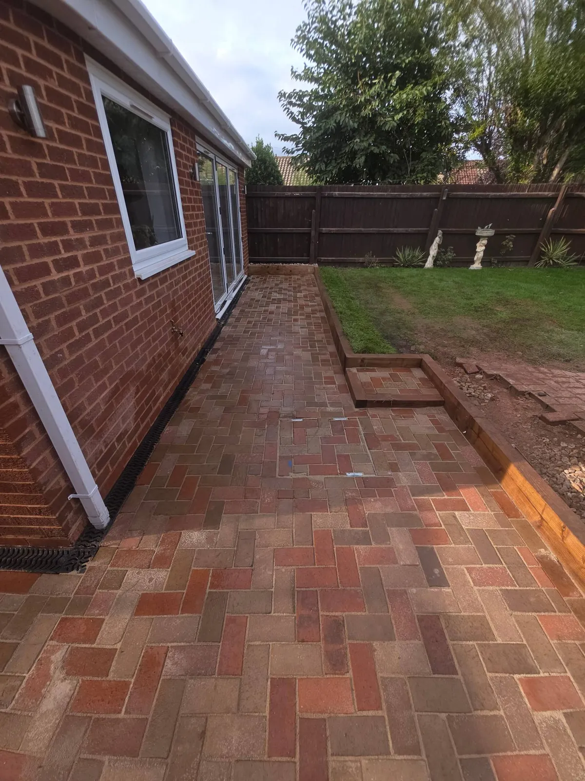 Red multi block paving beside a house with a sleeper retainer and step in Clayhanger