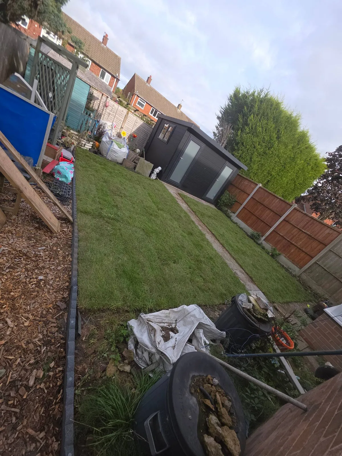 Newly turfed lawn with a new path leading to a garden room in Clayhanger